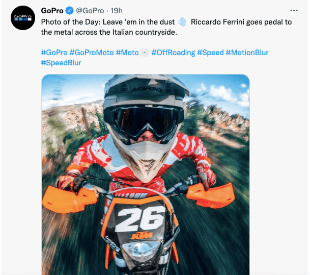 A social media post on Twitter from GoPro. The Tweet states, "Photo of the Day: Leave 'em in the dust [air puff emoji] Riccardo Ferrini goes pedal to the metal across the Italian countryside. The Tweet includes a photo of a man on a KTM motorcycle.